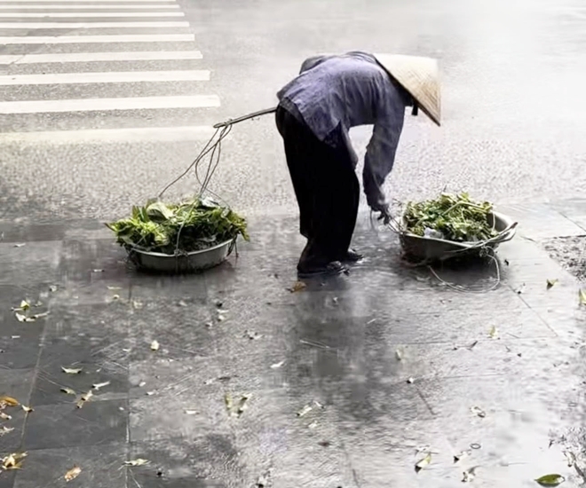 Cụ bà loay hoay với gánh rau giữa trời mưa trắng xóa