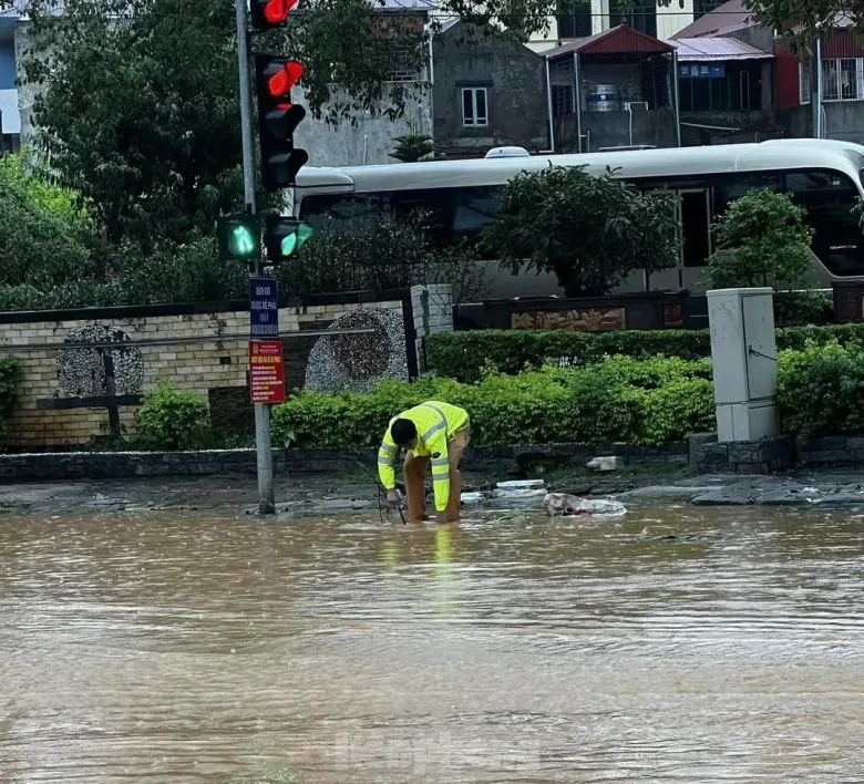 Chiến sỹ cảnh sát giao thông Công an Lạng Sơn vớt rác, khơi thông cống rãnh để nước rút nhanh.