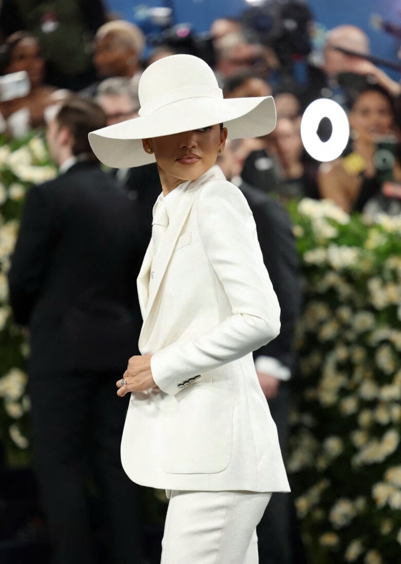 Zendaya chọn một bộ suit lụa trắng ba mảnh của Louis Vuitton. Mỹ nhân đình đám Hollywood chọn che đi một phần gương mặt bí ẩn bằng cách đội mũ rộng vành.