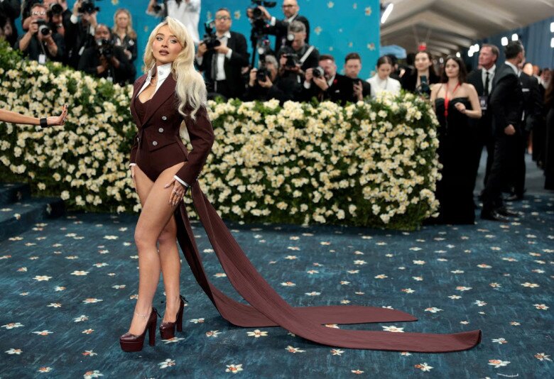 Sabrina Carpenter sải bước trên thảm đỏ Met Gala 2025 với bộ trang phục đầy cá tính: bodysuit màu nâu cà phê kết hợp với áo tuxedo dài đuôi tôm. Mái tóc bạch kim của cô cũng là điểm nhấn tại sự kiện thời trang đình đám.