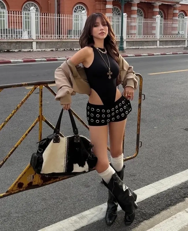 Một bạn trẻ kết hợp áo cùng quần shorts, bốt cao bồi và túi xách họa tiết da bò khi dạo phố.