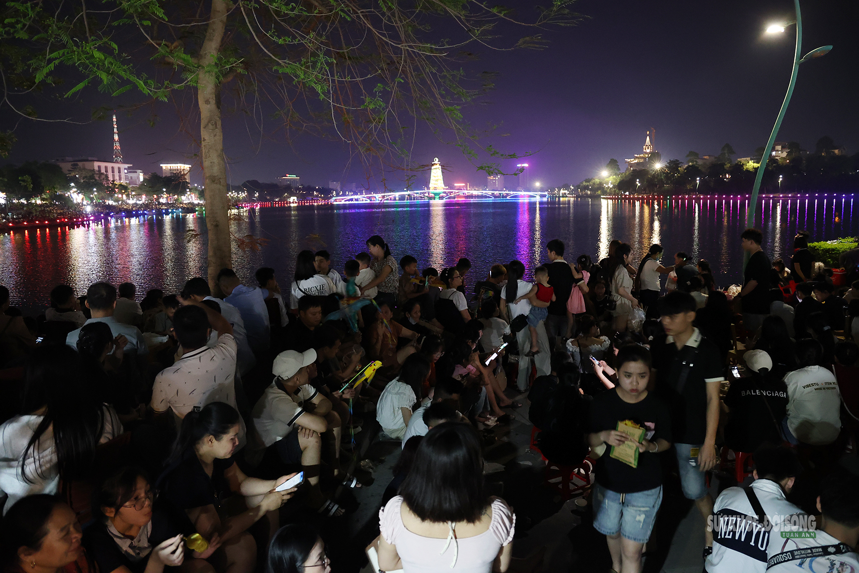 Khu vực ven hồ chật kín người; nhiều gia đình mang theo ghế nhỏ, đồ ăn nhẹ để chờ đến giờ bắn pháo hoa.