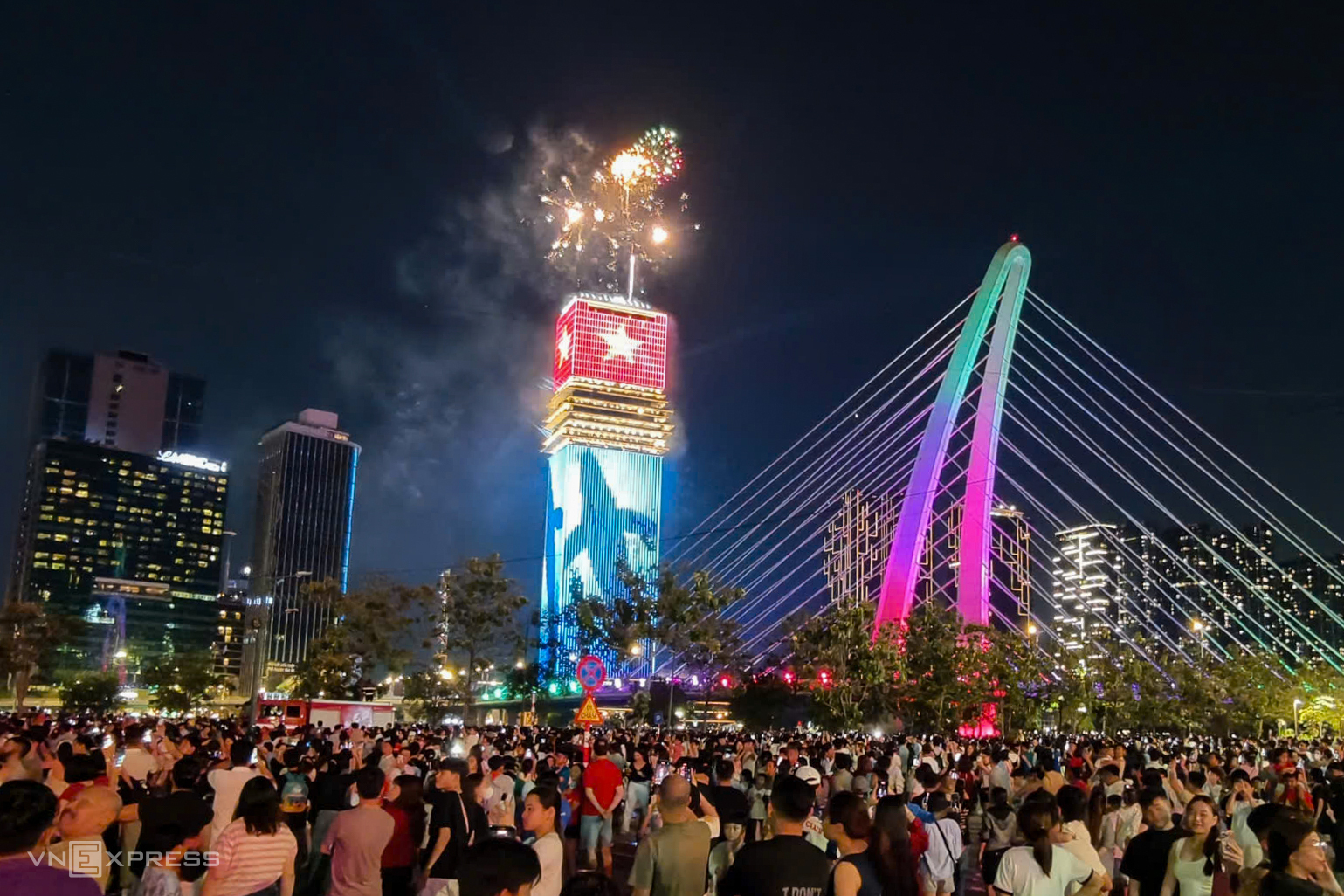Sau nhiều giờ chờ đợi, hàng nghìn người tại công viên bờ sông Sài Gòn, phường Thủ Thiêm, vỡ òa khi pháo hoa rực sáng trên bầu trời. Từ đây, người dân có thể chiêm ngưỡng pháo hoa bên sông Sài Gòn cùng tháp Saigon Marina IFC.