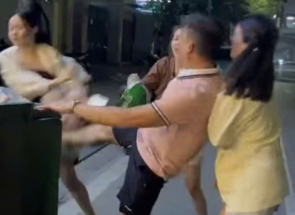Người đàn ông mặc áo hồng đạp vào bụng cô gái. Ảnh: Cắt từ clip
