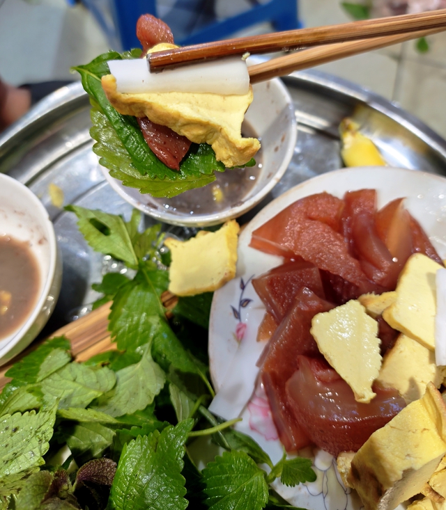 Món gỏi sứa đỏ được ăn bằng cách ghém sứa đỏ cắt miếng với rau thơm, đậu phụ nướng và dừa bánh tẻ lại với nhau, chấm cùng mắm tôm Ba Làng đã được pha mặn, ngọt, chua, cay. Ảnh: Đại Lâm Mộc