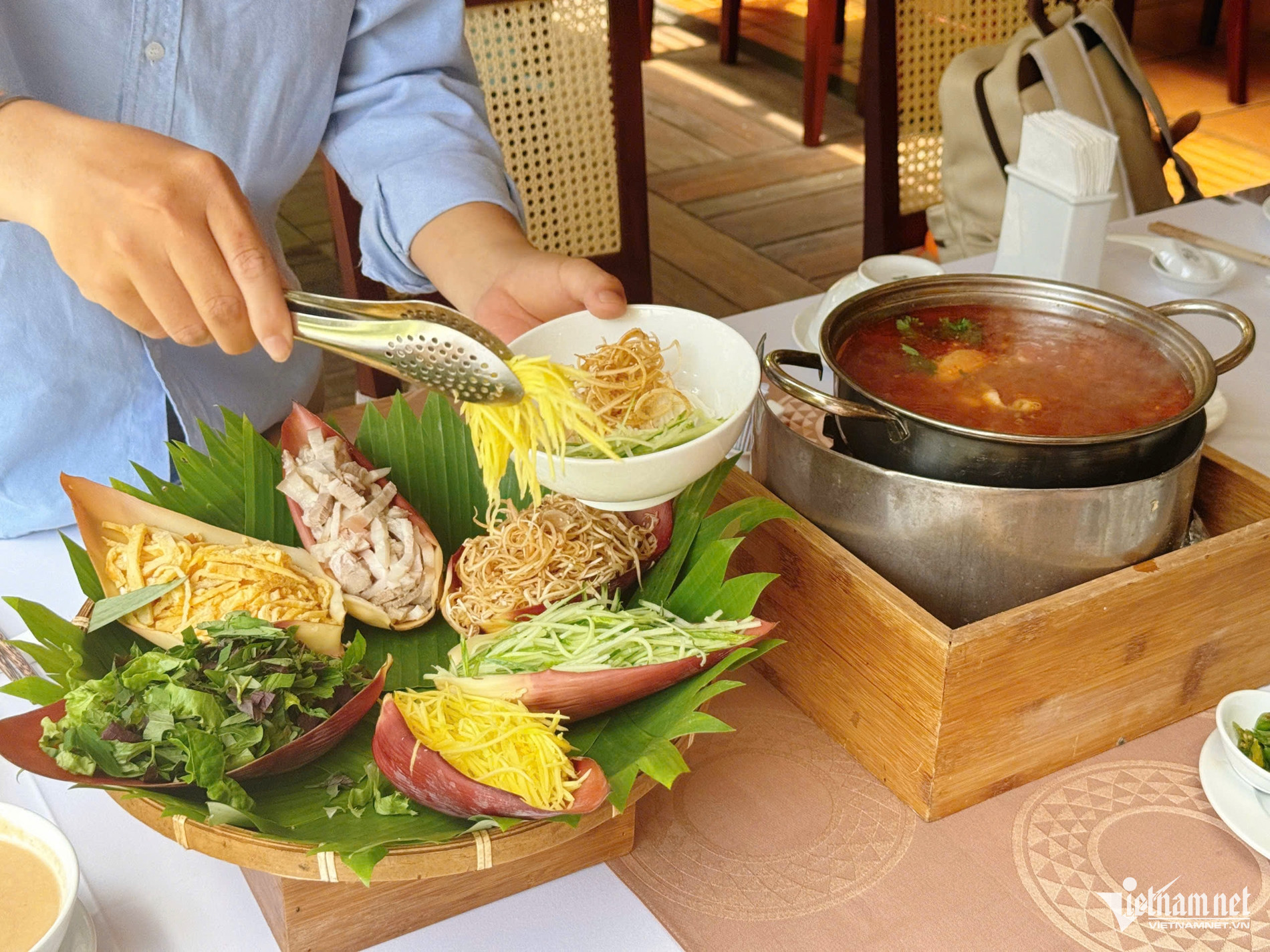 Món lẩu thả được tạo hình bông hoa đẹp mắt với phần “nhụy” là đĩa cá. Còn các cánh hoa đựng nguyên liệu ăn kèm được sắp xếp vào từng lớp bẹ chuối màu đỏ hồng