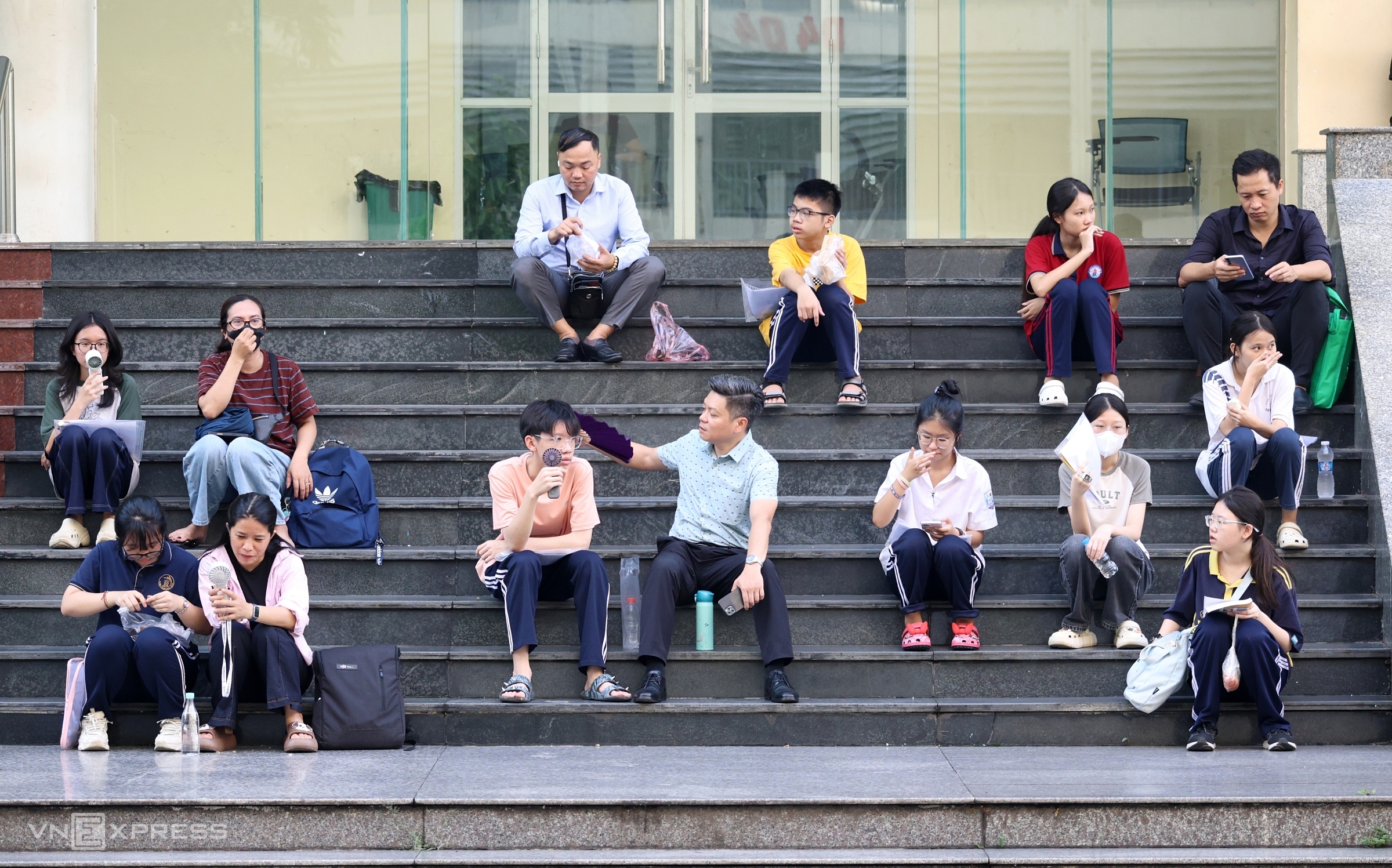 Thí sinh, phụ huynh ngồi chờ ở bậc thềm hội trường, trước giờ thi vào lớp 10 trường THPT chuyên Sư phạm, sáng 4/6. Ảnh: Thanh Hằng