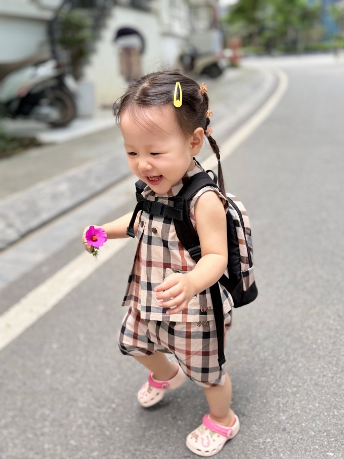 Em bé hai tuổi được mẹ cho diện trang phục họa tiết kẻ màu trung tính, đồng điệu với cặp sách và tết tóc hai bên khi đến trường. Phương Oanh nói con gái ngộ nghĩnh và ngọt ngào vì có nhiều biểu cảm hài hước, khiến trái tim mẹ tan chảy.