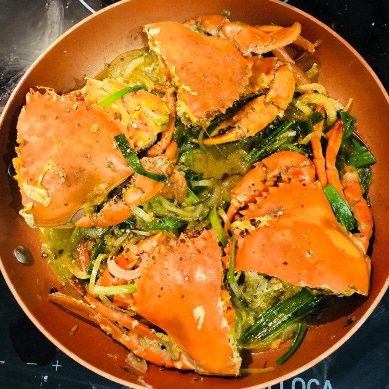 Chảo cua biển sốt mỡ hành và tiêu đen tỏa hương thơm nức mũi ngay trên bếp với lớp vỏ đỏ au bắt mắt. Từng thớ thịt cua săn chắc thấm đẫm phần nước sốt đậm đà, quyện cùng vị hăng nhẹ của hành tây và hành lá cắt khúc.