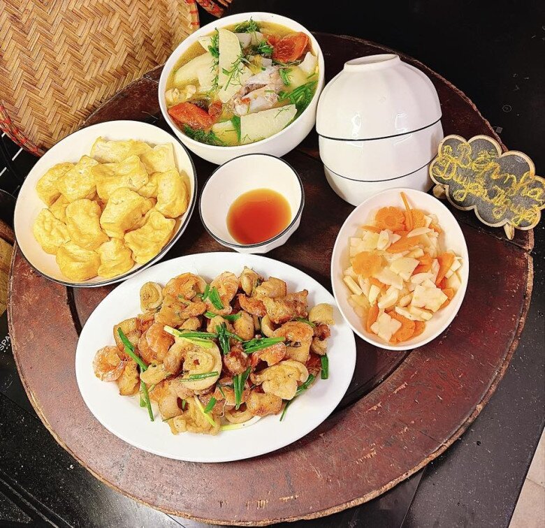 Mâm cơm này gồm các món: - Tôm rang thịt ba rọi tóp mỡ - Đậu phụ chiên - Canh cá trắm nấu củ hào - Dưa góp