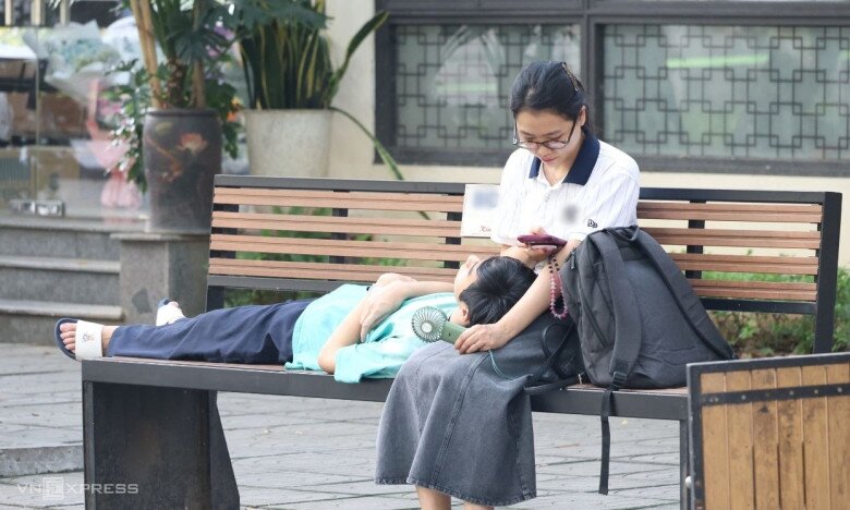 Chị Nguyễn Đỗ Trung tranh thủ cho con trai chợp mắt lúc 6h30, trong lúc đợi tới giờ thi. Ảnh: Thanh Hằng