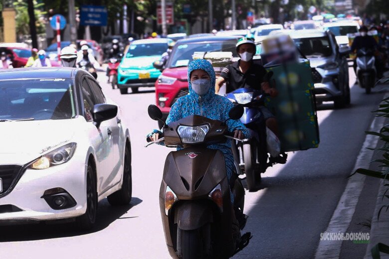 Người lao động di chuyển giữa dòng phương tiện trong thời tiết oi nóng, người đi đường đều che chắn kỹ khi ra ngoài.
