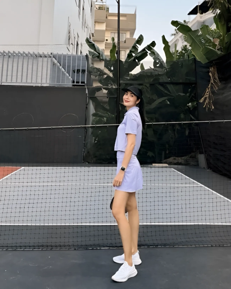 Nữ diễn viên tích cực tập ném bóng và trông rạng rỡ trên sân.