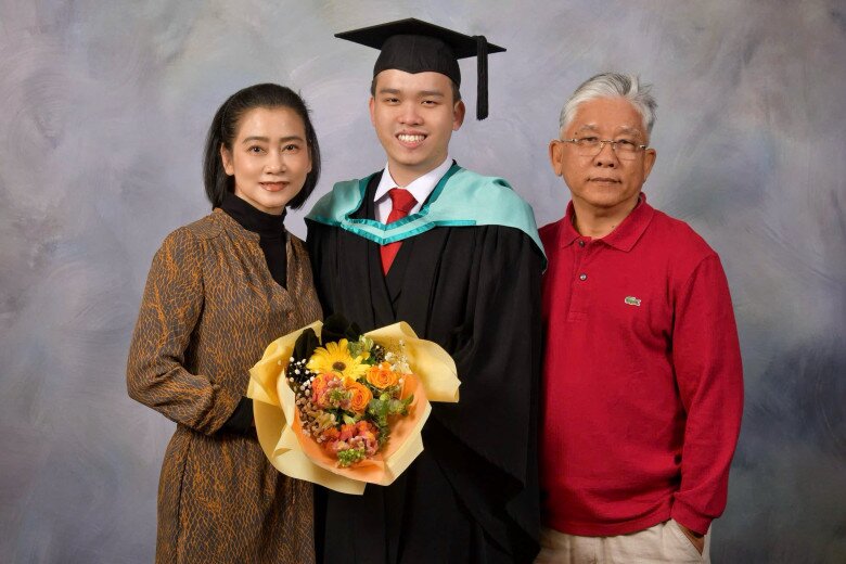 Anh chàng mặc trang phục cử nhân, chụp ảnh cùng bố mẹ.