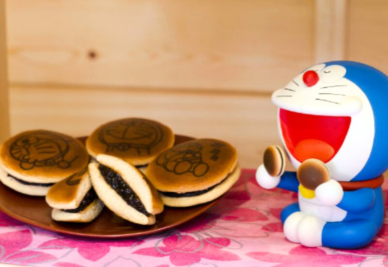 Bánh rán Doremon, hay dorayaki, là chiếc bánh tròn vàng ruộm gắn liền với phim hoạt hình đình đám đến từ Nhật Bản. Món này có vỏ mềm xốp, vị ngọt dịu, thường kẹp nhân đậu đỏ, socola hoặc kem sữa béo mịn.