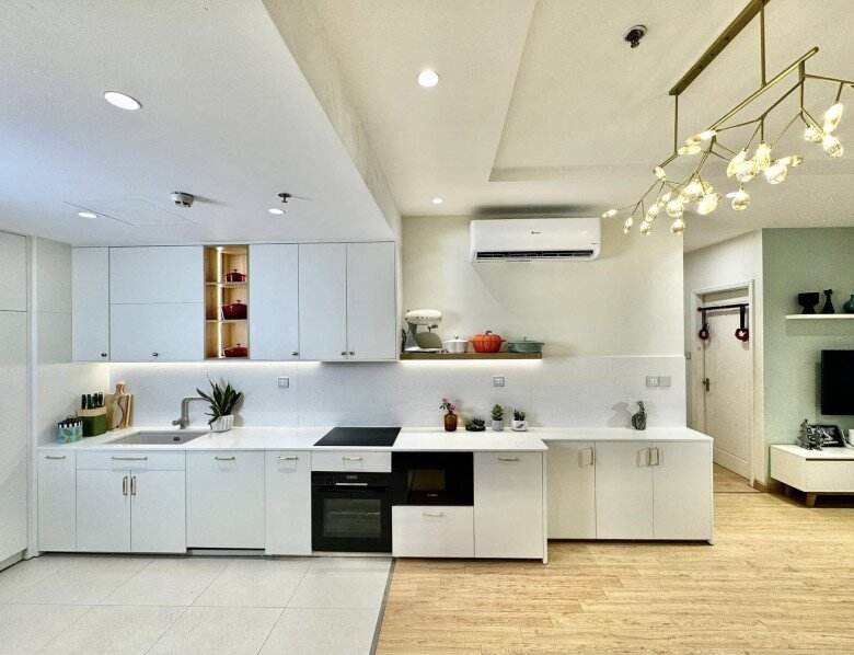 Mặt bếp bằng đá sáng màu tích hợp các thiết bị hiện đại, đối diện là khu vực sàn gỗ ấm cúng tạo sự phân tách tinh tế với sàn gạch khu vực nấu nướng.