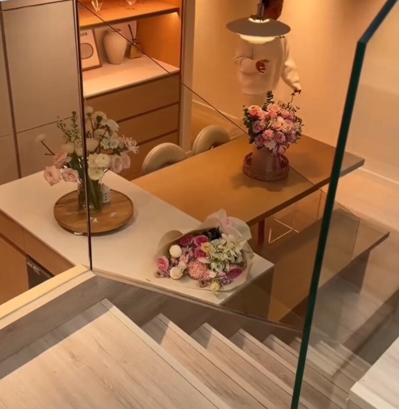 Góc nhìn từ cầu thang xuống khu vực bàn ăn, nơi được bài trí những bình hoa tươi rực rỡ, mang lại nguồn năng lượng tích cực và sự tươi mới cho căn nhà.