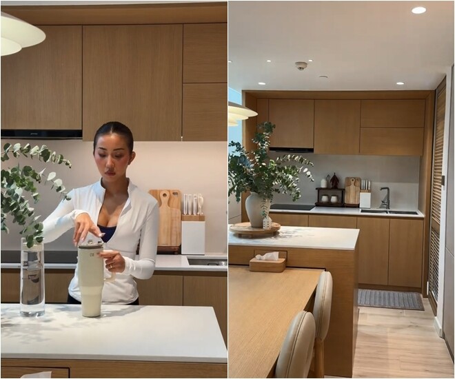 Gian bếp tiện nghi với hệ tủ gỗ sáng màu và mặt bếp đá trắng sạch sẽ. Những bình lá xanh được đặt khéo léo để mang thiên nhiên vào không gian nấu nướng.