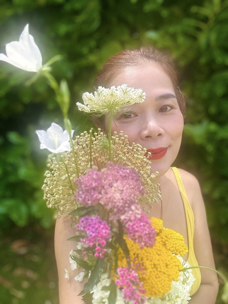 Nữ ca sĩ rạng rỡ e ấp bên bó hoa dại rực rỡ sắc màu vừa được hái trong vườn, mang lại nguồn năng lượng tươi mới của ngày hè ngọt ngào.