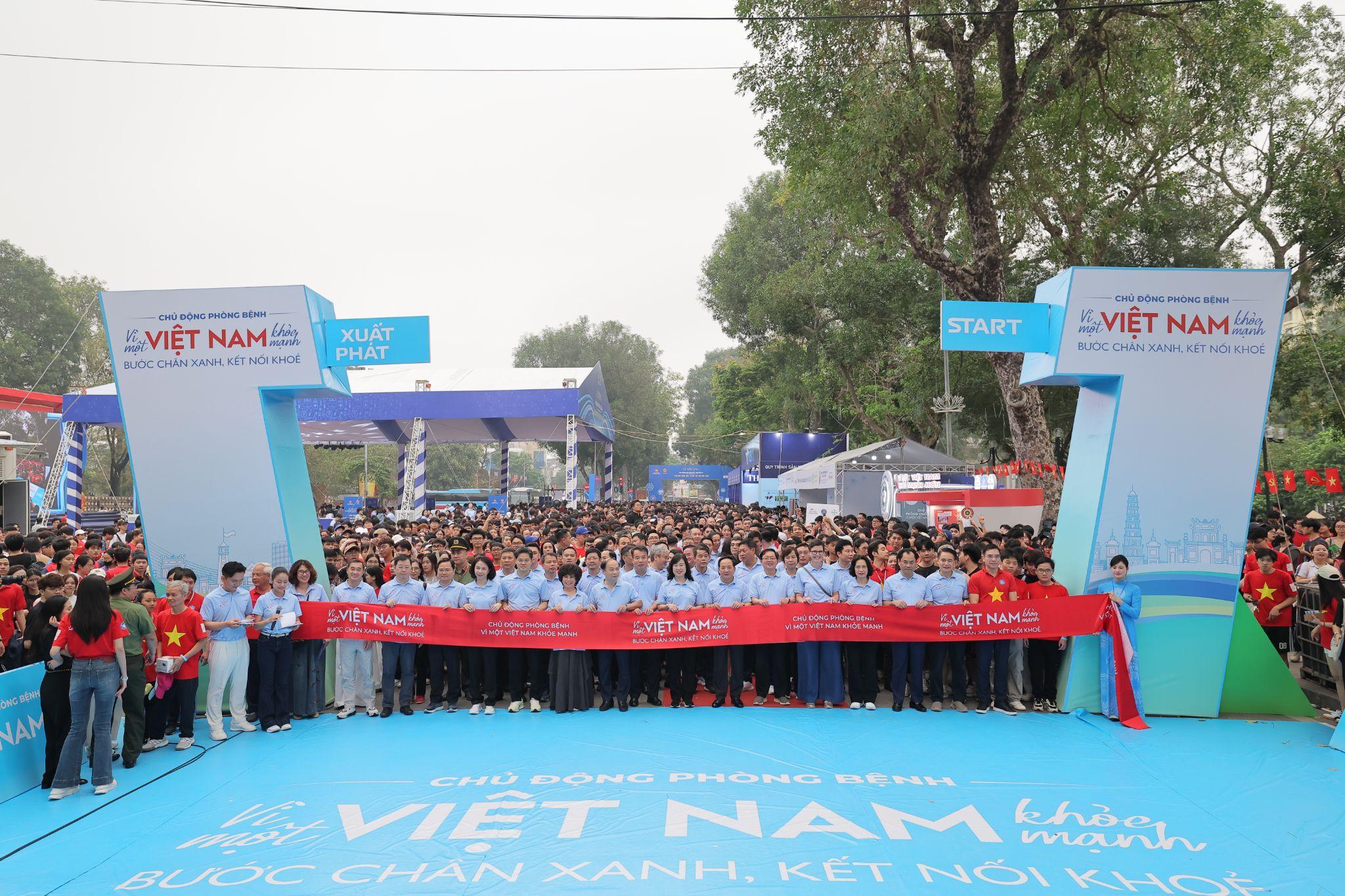 Mọi người đang đứng chuẩn bị tại vạch xuất phát để bắt đầu giải đi bộ Vì một Việt Nam khoẻ mạnh - Bước chân xanh, kết nối khoẻ