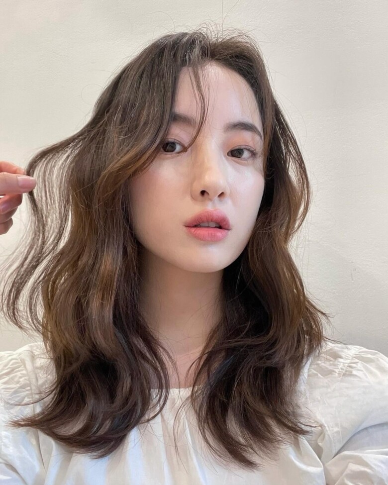 Tóc ngang vai uốn xoăn tạo độ bồng bềnh tự nhiên, giúp mái tóc trông dày hơn rõ rệt. Những lọn xoăn nhẹ giúp gương mặt mềm mại, cân đối, đồng thời mang lại vẻ ngoài cuốn hút, phù hợp nhiều phong cách khác nhau.