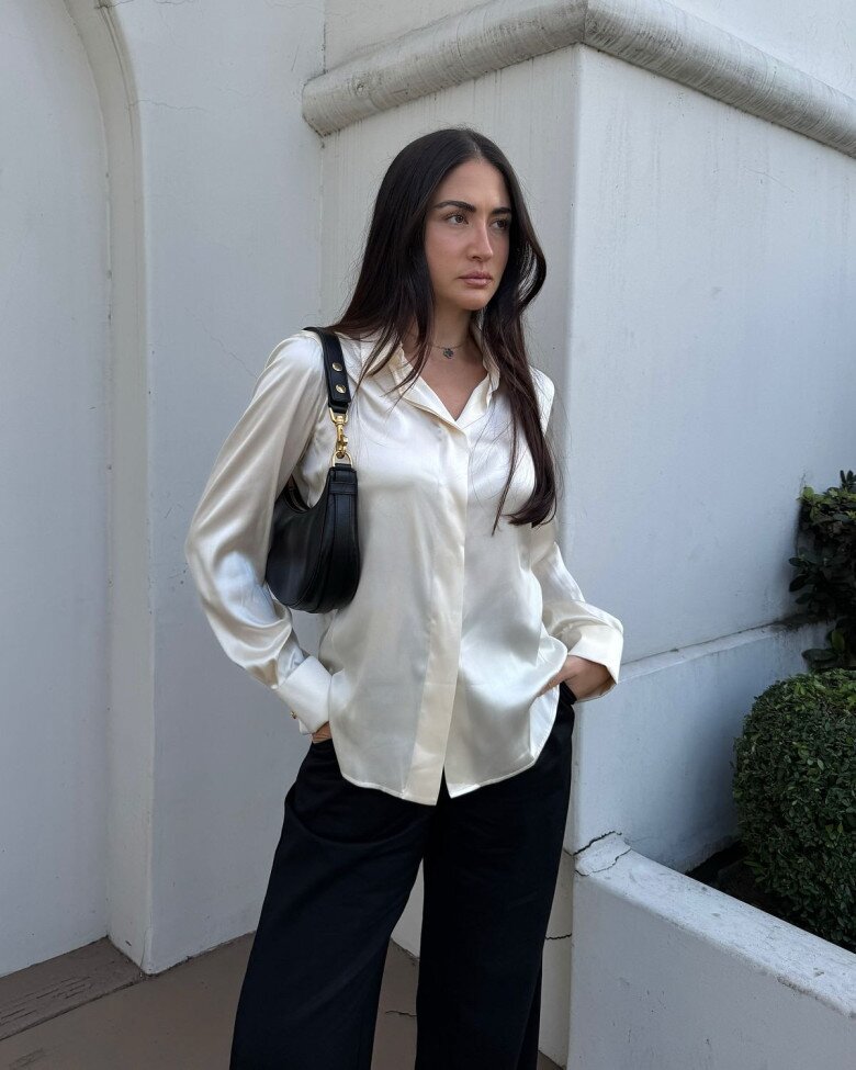 Áo sơ mi lụa giúp outfit trông thanh lịch và mềm mại hơn mà không cần phối quá cầu kỳ. Chất liệu có độ bóng nhẹ tạo cảm giác tinh tế cho tổng thể. 