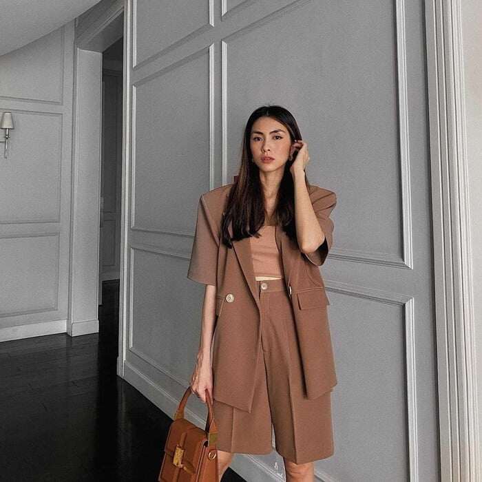 Chị em công sở thích phong cách năng động có thể tham khảo cách Tăng Thanh Hà mix blazer cộc tay và quần shorts dáng suông gam màu nâu trang nhã, layer bên trong một chiếc crop top cùng tông.