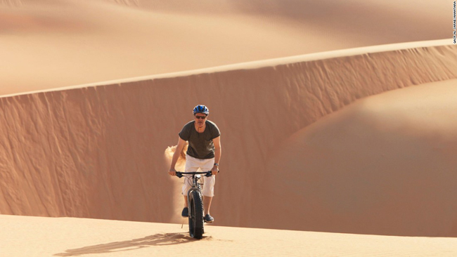 Để tránh ánh nắng mặt trời thiêu đốt, du khách có thể dạo quanh sa mạc trên xe đạp bánh to lúc sáng sớm.
