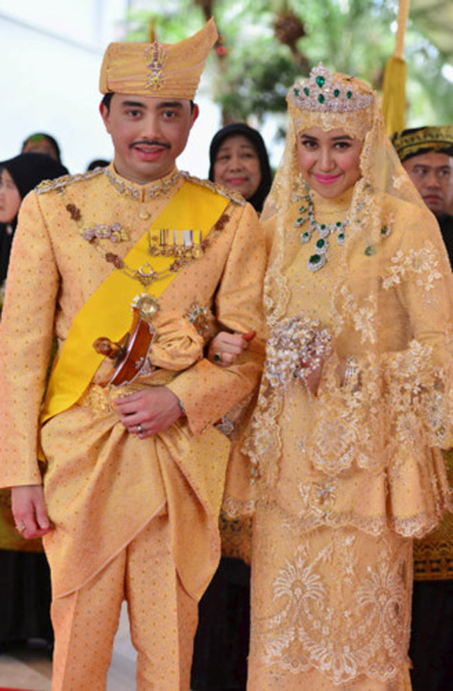 Vợ Hoàng tử Brunei được thiết kế theo lối trang phục truyền thống. Bộ trang phục có mức giá khủng khi phần ren mạ vàng,  thân váy được đính viên kim cương và đá quý. Hai vợ chồng thể hiện "quyền lực ngầm" thông qua trang đám cưới.
