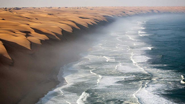 Nơi sa mạc Namib gặp biển Atlantic

Những cồn cát vàng óng ánh trải dài như bất tật, đôi chỗ xuất hiện những đám cây xanh cùng một vài động vật lang thang đi dạo…Sa mạc Namib hiện lên vừa quyến rũ lại đầy bí ẩn.

Thế nhưng không khí trên sa mạc Namib bớt khắc nghiệt hơn nhiều khi được làm mát bởi biển Atlantic – Đại Tây Dương.

Dòng nước mát lạnh của biển khơi đánh dạt lại bờ cát của sa mạc Namib tạo nên một khung cảnh đẹp mơ màng và kì ảo mà ai cũng muốn được một lần chiêm ngưỡng trong đời
