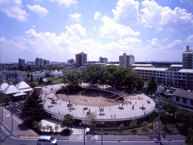 Được xây dựng từ năm 2007, trường mẫu giáo Fuji ở Tachikawa, Nhật Bản có thiết kế vòng tròn rất ấn tượng với phần mái nhà giống như một sân chơi mà trẻ em có thể tha hồ vui chơi và chạy nhảy, thậm chí leo trèo lên cây.
