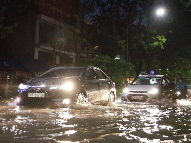 Dân Hà Nội loay hoay quét nước ra khỏi nhà sau cơn mưa như trút