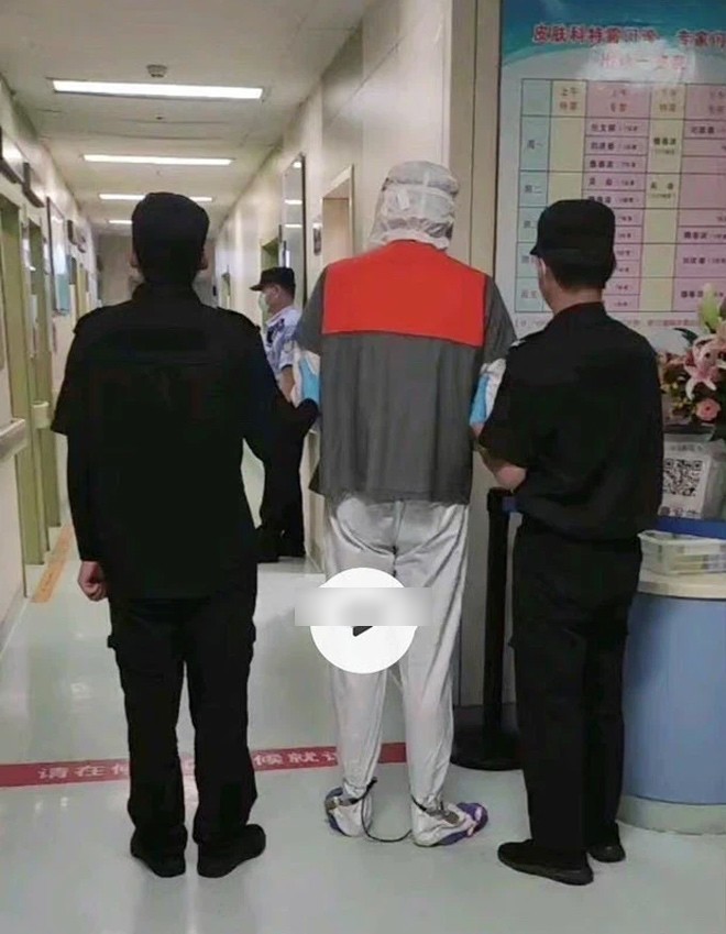 Nhân vật trong hình được cho là nam tài tử bị xích chân và còng tay, trùm kín mặt.