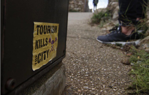 Một tờ rơi với nội dung Du lịch giết thành phố này được dán sau một cuộc biểu tình tại châu Âu - Ảnh: Alamy.