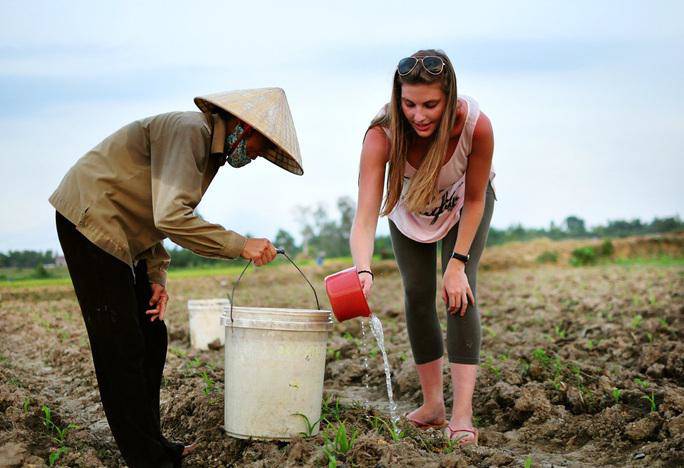 Một khách du lịch nước ngoài tham gia tưới nước cho ngô cùng người dân địa phương - Ảnh: Thành nhà Hồimg src/upload/3-2022/images/2022-08-14/1660486590-980938109da198990fe049708a95b4e9.jpg width660 /