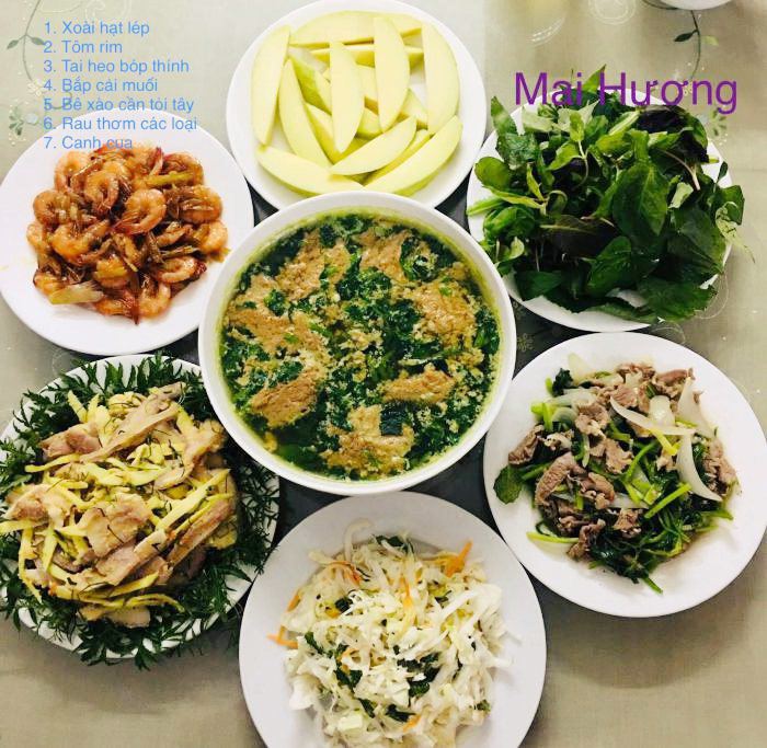 Bữa cơm gồm: Xoài hạt lép, tôm rim, tai heo bóp thính, bắp cải muối, bê xào cần tỏi tây, rau thơm các loại, canh cua. 