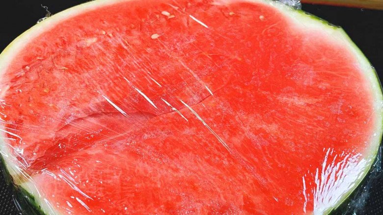 A piece of watermelon wrapped in plastic wrap