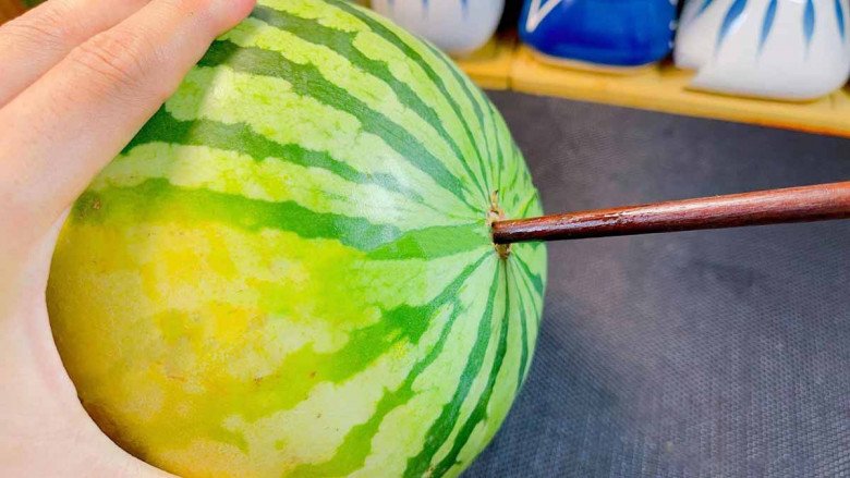 A watermelon with a chopstick piercing its bottom