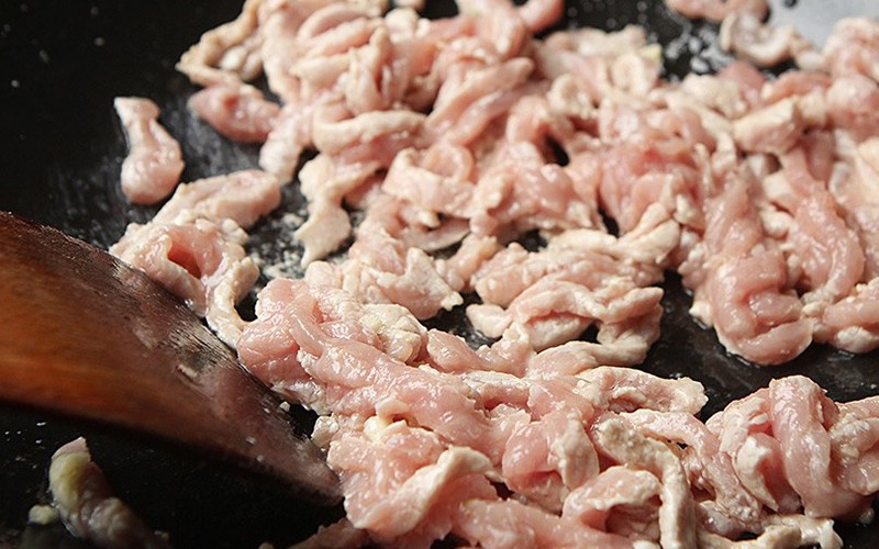 Cho dầu ăn vào chảo, đun nóng đến khoảng 60%, cho thịt lợn đã thái nhỏ vào xào trong 30 giây rồi cho ra đĩa.
