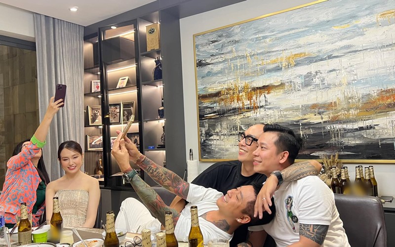 Tuấn Hưng say sưa chụp ảnh cùng Lê Hoàng tại nhà đàn em. Phòng ăn nhà Lê Hoàng - Việt Huê dễ nhận ra với bức tranh ấn tượng trên tường cùng hệ tủ kệ sang trọng.

