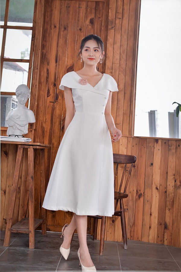 A woman wearing a white midi dress with a classic twist