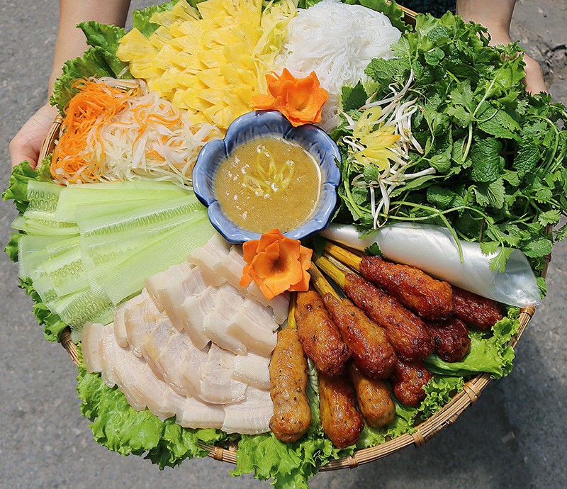 Mẹt này gồm bánh tráng cuốn nem lụi, thịt luộc, và các loại rau quả ăn kèm.
