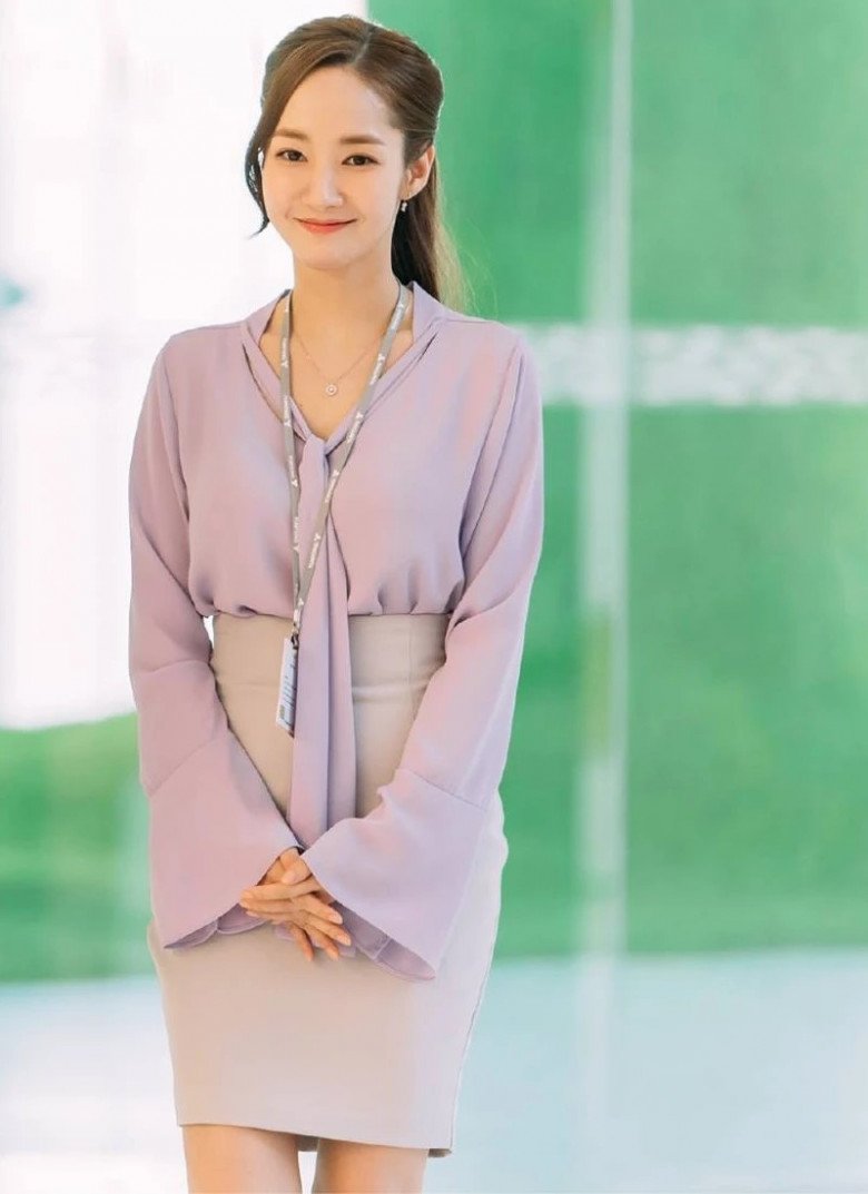 Chiếc áo blouse tím có phần dây lụa dài ở cổ của nữ diễn viên Park Min Young đi cùng chân váy bút chì xám nhạt tạo tổng thể hài hòa và cân đối cho người mặc. 