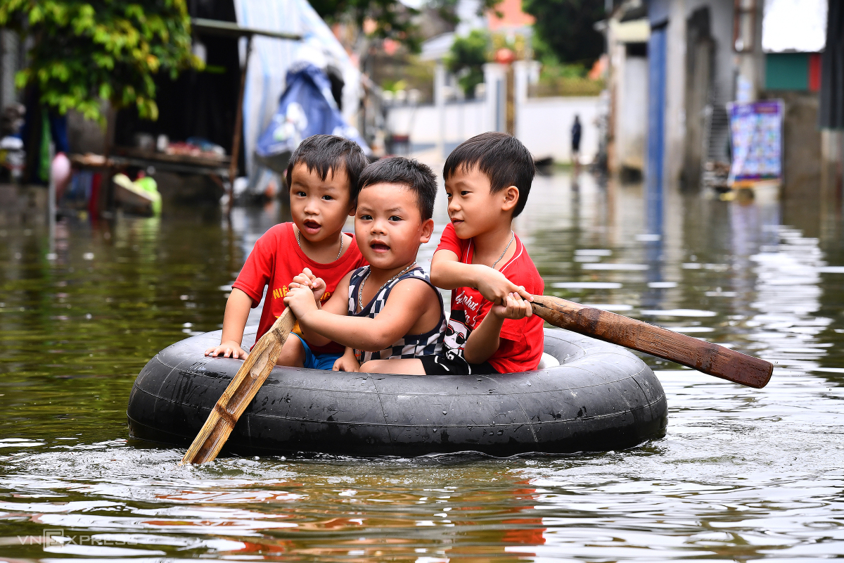 Các em bé thôn Nam Hài đang chơi đùa bằng thuyền tự chế ngay trước cửa nhà mình. 