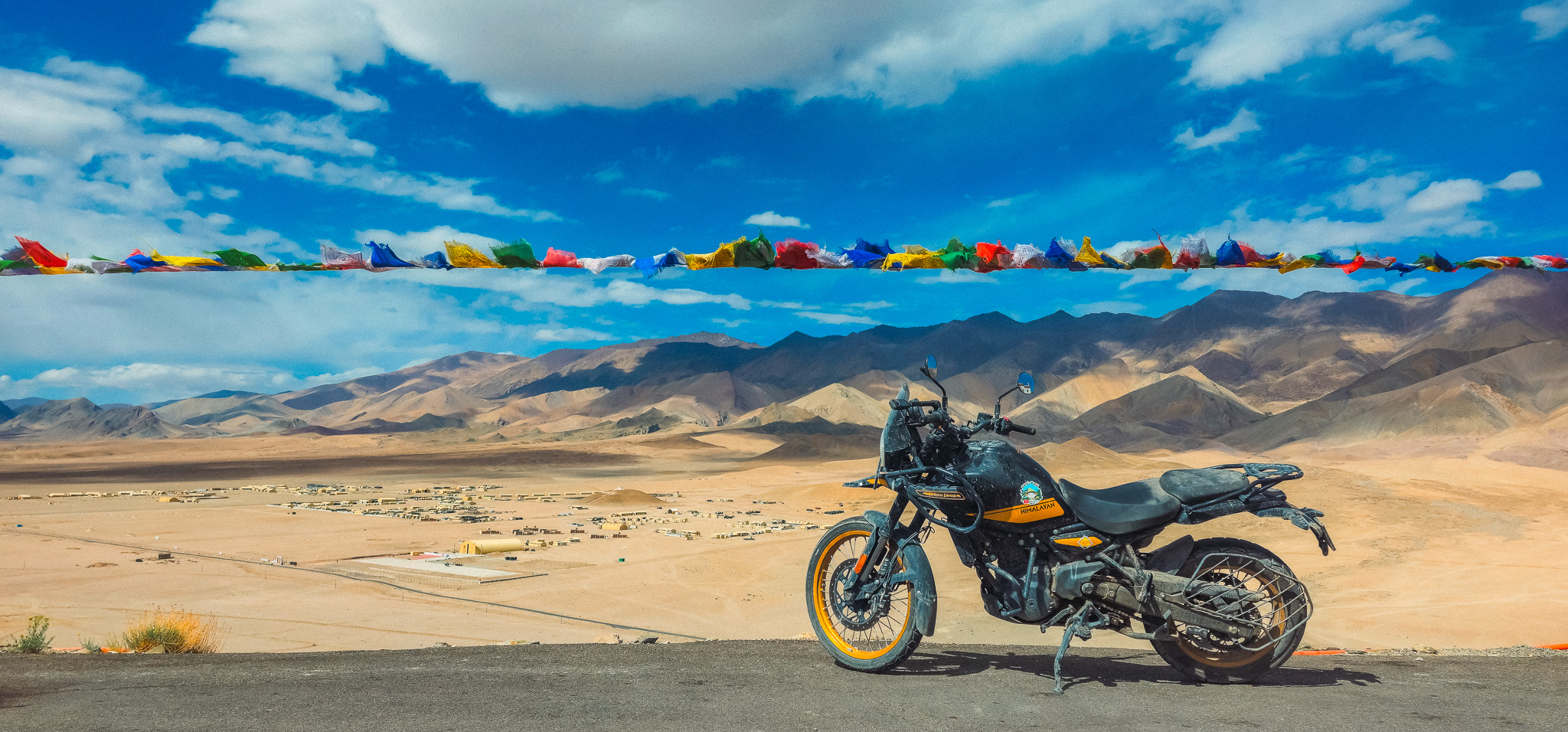 Vinh Gau, a travel blogger, poses with his motorcycle under a row of Lungta flags