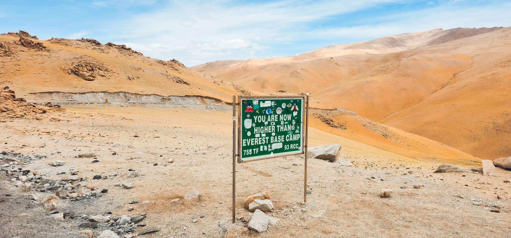 A motorcycle rider poses on a winding road with a vast valley below