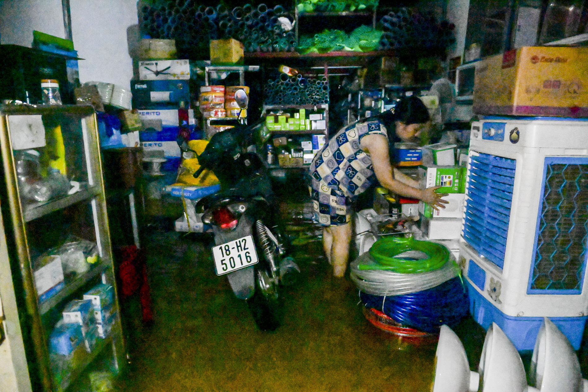 Cô Trần Kim Huệ (50 tuổi) hối hả đưa đồ điện lên vị trí cao.