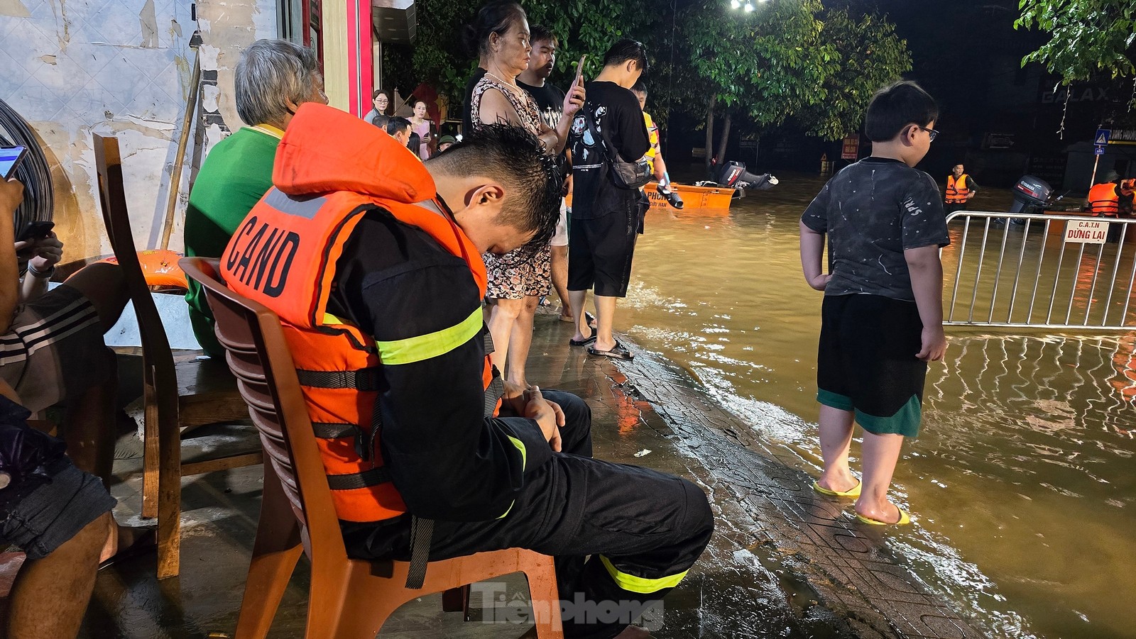 Bữa cơm đơn giản của các cán bộ, chiến sĩ trong giờ phút giải lao sau những chuyến xuồng cứu trợ người dân. Một chiến sĩ công an trẻ tranh thủ chợp mắt dù quần áo đang ướt và trên người vẫn mặc áo phao. Theo ghi nhận của phóng viên, nhiều cán bộ, chiến sĩ quân đội, công an làm việc xuyên ngày đêm để cố gắng cứu người dân. Ảnh: Hoàng Mạnh Thắng - Trường Phong.