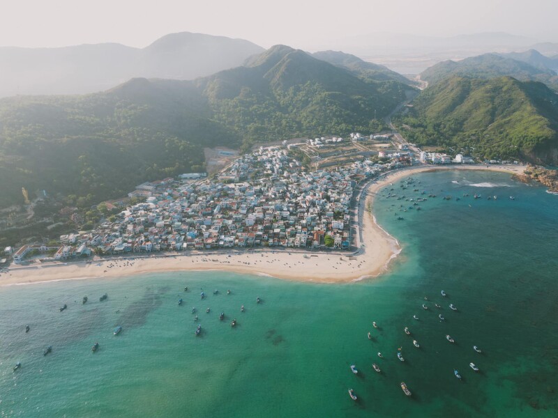 Tách bạch hoàn toàn khỏi nhịp sống thị thành náo nhiệt, Làng chài Nhơn Hải thuộc khu vực ngoại ô thành phố với khung cảnh biển xanh, cát trắng và đồi núi dốc đá lởm chởm, vẽ nên bức tranh dung dị, giản đơn. (Ảnh: Bùi Ngọc Lâm)