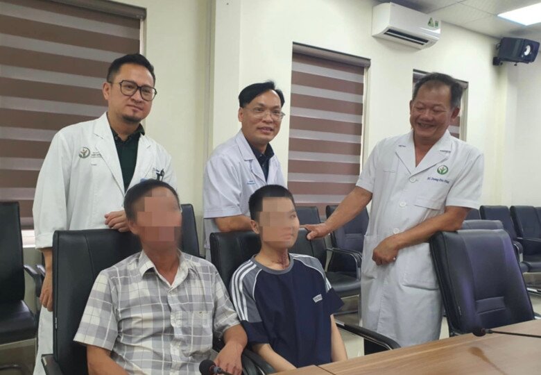 Hai bố con bệnh nhân (ngồi) cùng các bác sĩ BV Việt Đức trong ngày tái khám sau hơn 3 tháng thực hiện ca ghép khí quản. Ảnh: Thu Trang.